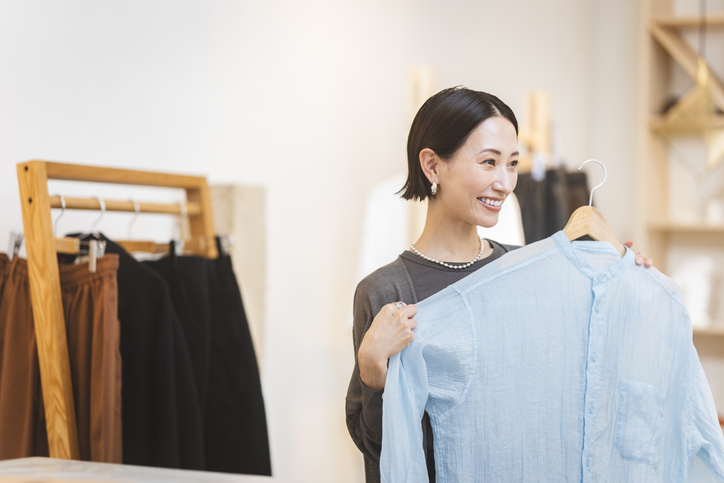 A Japanese woman is choosing clothes at a store.